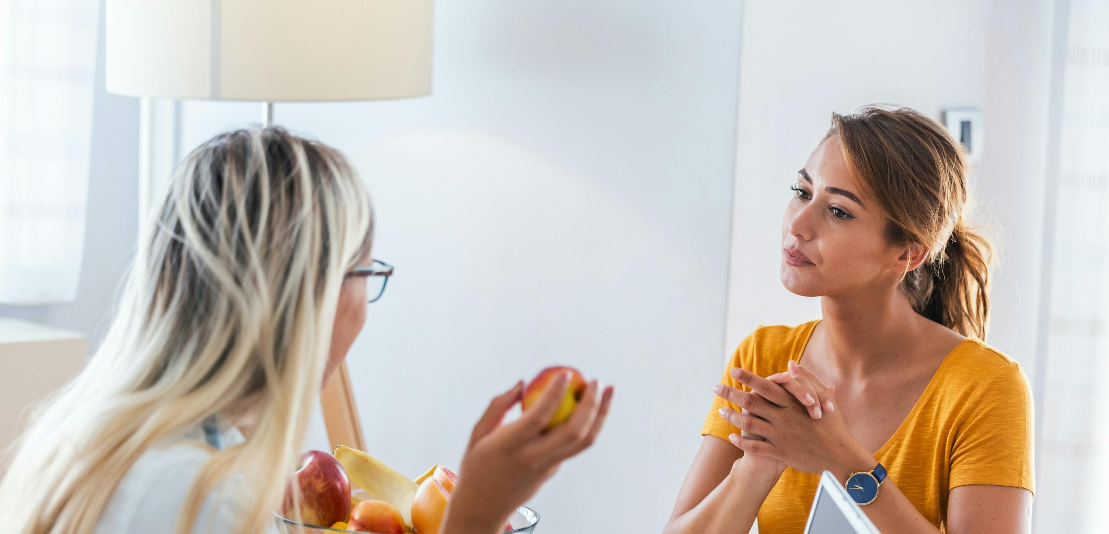 Two women at a table; one providing nutritional education