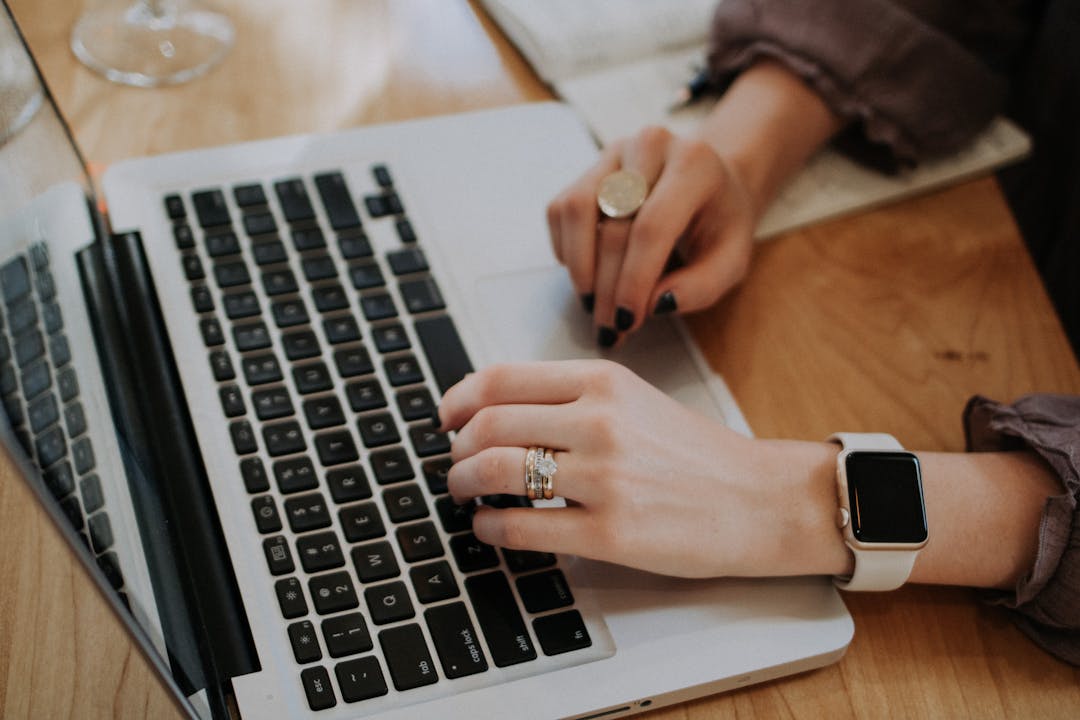 a woman wearing an apple watch - using a MacBook on a table