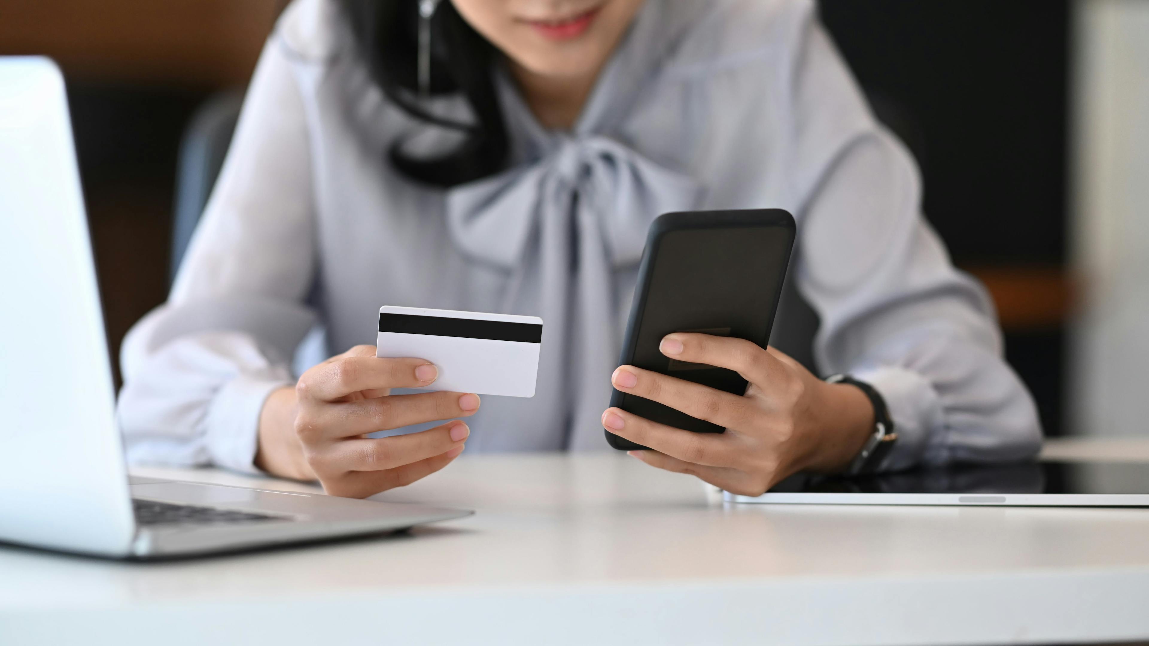 A woman holding a card and a mobile phone