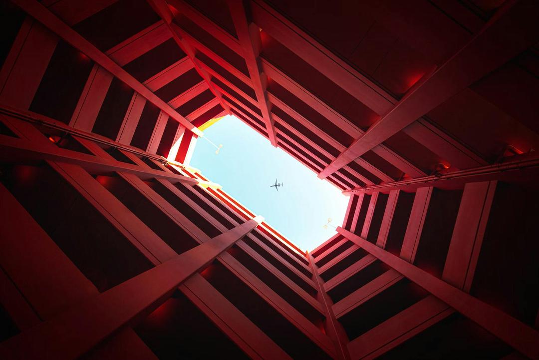 plane in blue sky seen through towers