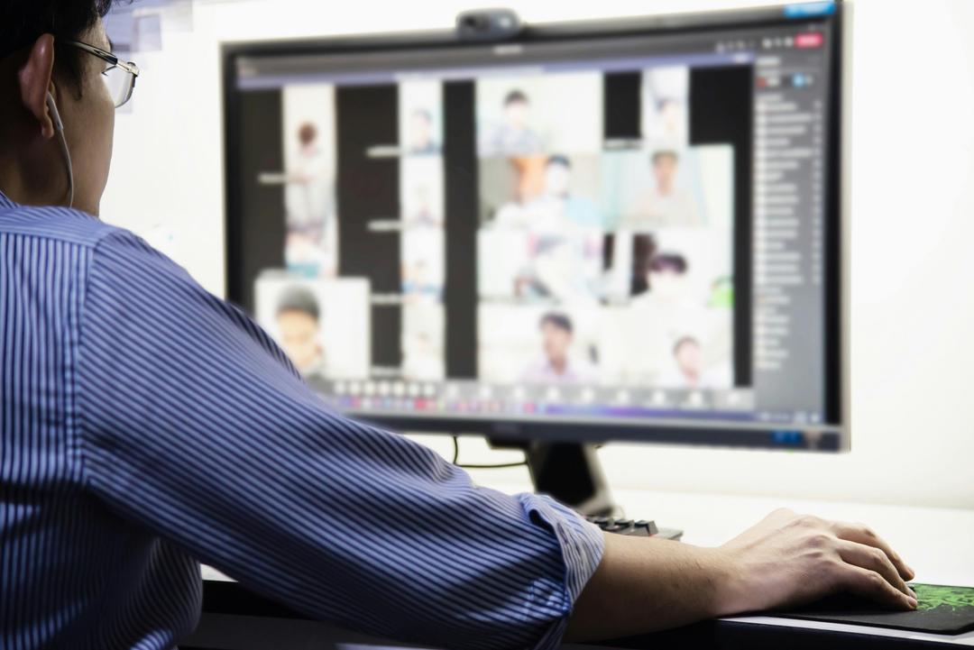 person looking at a computer screen with blurred videos within in a call