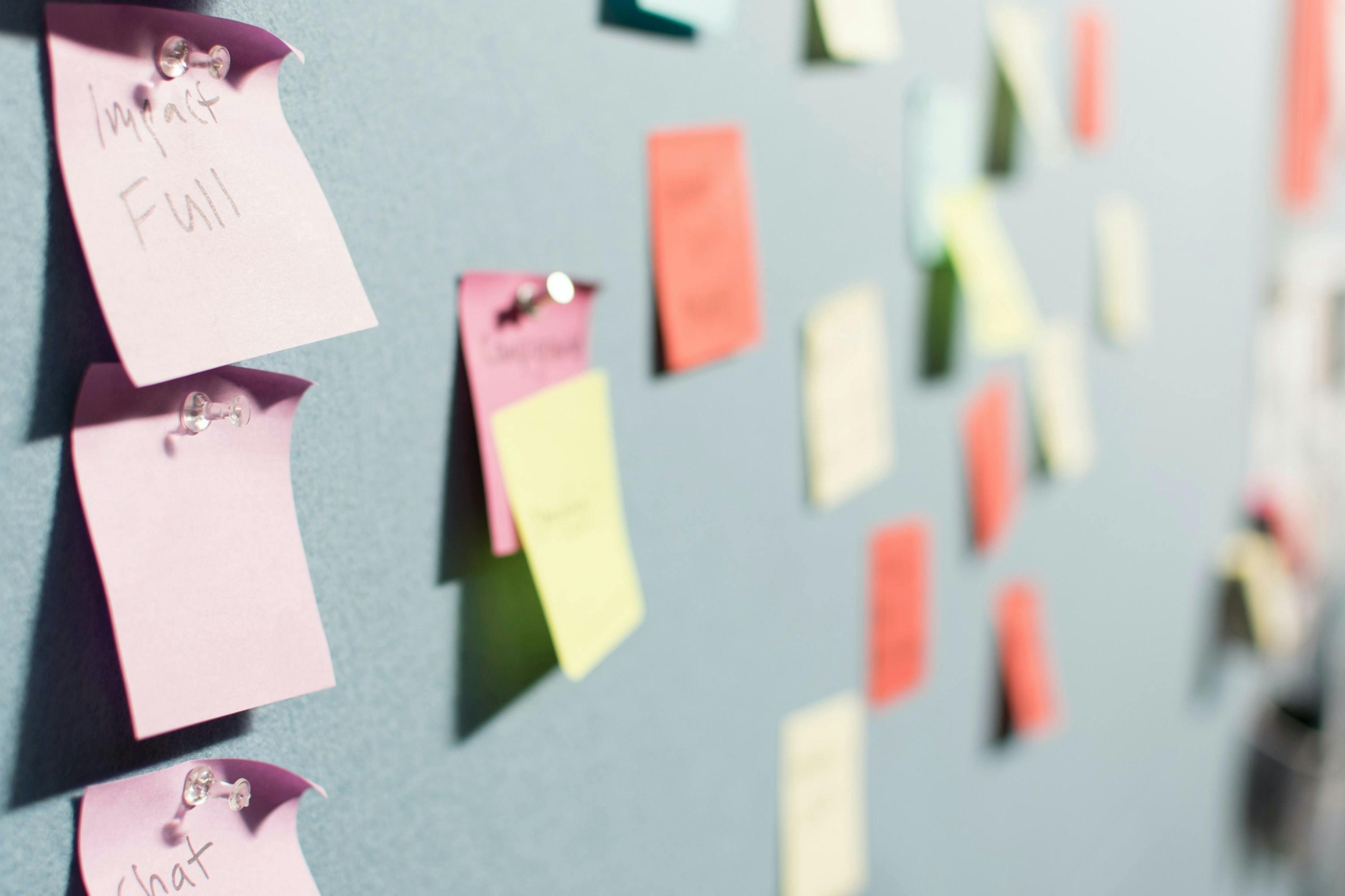 post-its pinned on gray cork board